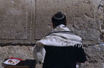 A Jewish man wearing a traditional prayer shawl praying at the Western Wall.Also known as The Wailing wall