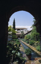 The Generalife.  Long central pool in the Patio de la Acequia enclosed oriental garden framed by archway. Andalusia