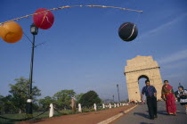 India Gate with a family walking along the road near colourful lanterns