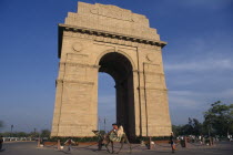 India Gate.  Man leading camel past carrying three children