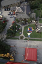 View from cage over falling bungee jumper  inflated safety mat and spectators.
