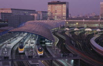 Waterloo Station International Terminal with Eurostar trains in evening.  City buildings behind.