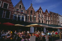 The Markt  Market Place   Line of cafes with busy outside tables under green awnings and red umbrellas with menus displayed at side.