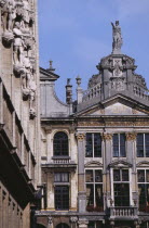Part view of facades of guild houses in Grand Place with gable rooftops and carved stone statues.
