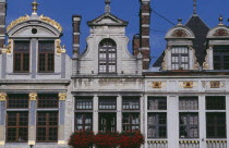 Part view of building facades with gable rooftops and gilded decoration  balconies and flower filled window boxes.