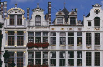 Part view of building facades with gable rooftops and gilded decoration  balconies and flower filled window boxes.