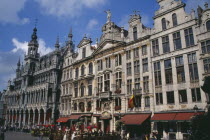 Grand Place.  Maison du Roi on left beside decorative facades of old town buildings  busy outside tables of cafe and people crossing square.UNESCO World Heritage Site  UNESCO World Heritage Site