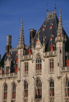 The Markt  Market Place . Exterior facade of old town building with red painted window frames  roof vents and gables with spires and gold statue of the archangel Michael slaying the devil.   Flemish...