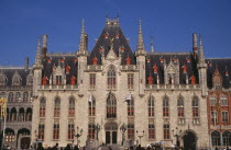 The Markt  Market Place . Exterior facade of old town building with red painted window frames  roof vents and gables with spires and gold statue of the archangel Michael slaying the devil.   Flemish...