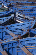 Prows of blue and green fishing boats moored closely together.
