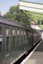 Steam Railway Station. View along platform with train departing from station and conductor seen looking out from carriagesGreat Britain United Kingdom UK