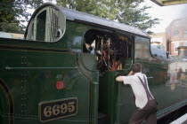 Steam Railway. Train driver leaning against train engine waiting in stationGreat Britain United Kingdom UK