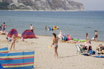 Sandy beach with girls playing Bat and Ball amongst sunbathers on sand and swimming in the seaGreat Britain United Kingdom UK