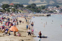 View along the shoreline of sandy beach with sunbathers on the sand and swimming in the seaGreat Britain United Kingdom UK