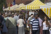 French Market. People looking around yellow and white striped covered market stalls  Great Britain United Kingdom UK