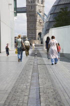 People walking passed man made stream toward GLA town hall and Tower Bridge.United Kingdom  Southbank Great Britain UK