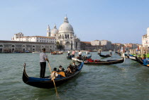 Gondolas with sightseeing tourists on the Grand Canal in front of the Baroque church of Santa Maria della Salute