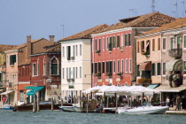 Boats on the Canale Grande di Murano moored beside restuarants on the Fondamenta Cavour busy with tourists sightseeing