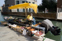 A fruit and vegetable vendor with his boat moored alongside the Fondamenta dei Vetrai along the Rio dei Vetrai canal on the lagoon island of Murano