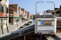 A mechanically operated wheelchair ramp on a bridge across the Rio dei Vetrai canal on the lagoon island of Murano