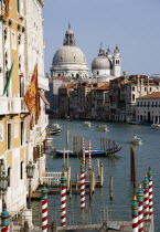 The Byzantine church of Santa Maria della Salute with water taxis passing along the Grand canal towards Palazzo Franchetti Cavali decked with flags  the palace once owned by Archduke Frederick of Aust...