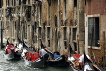 Gondoliers resting with their gondolas moored at the edge of the Rio Dei Barcaroli canal in San Marco district