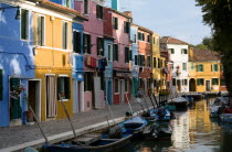 Colourful houses beside a canal on the lagoon island of Burano with boats moored alongside the edge of the canal Colorful