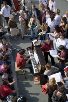 The Paris Plage urban beach. A singer playing a piano to an audience under the Pont Notre Dame on the Voie Georges Pompidou a usually busy road closed to traffic