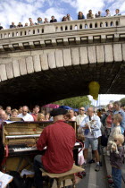 The Paris Plage urban beach. A singer playing a piano to an audience under the Pont Notre Dame on the Voie Georges Pompidou a usually busy road closed to traffic