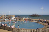 Childrens paddling pool with the ruins of the West Pier behind.Great Britain United Kingdom