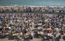 People sat at tables drinking outside the Beach seafront bar.Great Britain United Kingdom