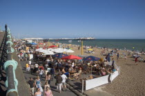 People sat at tables outside seafront bars and cafes.Great Britain United Kingdom