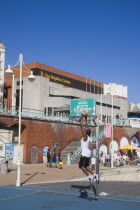 Young man playing basketball on the seafront court with the Brighton Centre behind.Slam dunk Center Great Britain United Kingdom