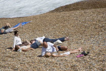 Family on the stoney beach at Hove with father covering son with pebbles.Great Britain United Kingdom