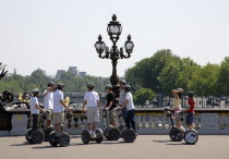 Children on the Pont Alexandre III across the River Seine. Touring on electric self balancing scooters  or two wheeled gyroscopic platformEuropean French Kids Western Europe