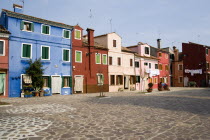 Colourful houses in a square on Burano. One of the few inhabited islands in the lagoon. Laundry hanging to dry outside windows.  Colorful