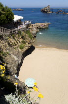 The Basque seaside resort on the Atlantic coast. The Plage de Port-Vieux with a seafood restaurant on a promontory at the end of the beach and the Rocher de la Vierge out to sea