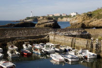 The Basque seaside resort on the Atlantic coast. Boats in the safe harbour of the Port des Pecheurs with the lighthouse in the distance.
