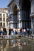 Aqua Alta High Water flooding in St Marks Square with tourists queuing on elevated walkways to enter St Marks BasilicaPaul Seheult