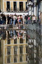 Aqua Alta High Water flooding in St Marks Square with tourists queuing on elevated walkways to enter St Marks Basilica