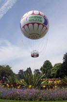 The Bournemouth Eye balloon lifting off in The Upper Pleasure Gardens with tourists on the grass and the pathways