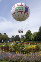 The Bournemouth Eye balloon lifting off in The Upper Pleasure Gardens with tourists on the grass and the pathways