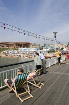 The West Beach from The Pier with the BICC Bournemouth International Conference Centre and Oceanarium in the distance. Tourists on deckchairs on the pier