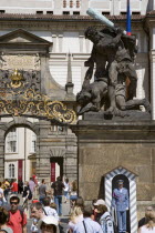 Tourists at the entrance to Prague Castle with a sentry standing guard beneath an 18th Century statue of fighting giants by Ignaz Platzer