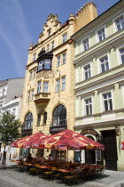 Tables and umbrellas on the pavement outside a cafe in a sidestreet of the Old Town