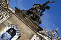 Soldier standing guard at a sentry box below an 18th Century statue of fighting giants by Ignaz Platzer at the entrance to Prague Castle