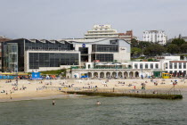 The Imax Complex on the seafront with people on the beach and in the water by a small pier jetty