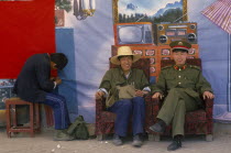 Chinese police pose in front of backdrop featuring desirable electrical goods in domestic interior  equipment they are unlikely to have in reality.