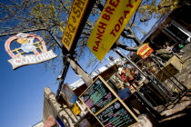 The Cowgirl Cafe outdoor eating area with customers and a waiter. Sign showing the days meals