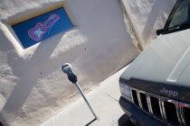 Illuminated Budweiser sign and electric guitar in window of Blues Club with parking meter and parked jeep in the foreground